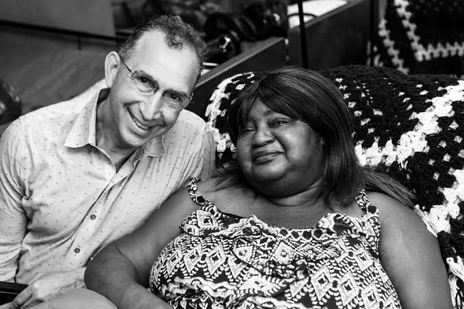 David Ansell seated with a community resident